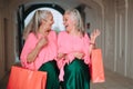 Happy senior women twins in colourful clothes in city, shopping.