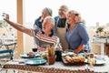 Happy seniors friends taking selfie with mobile smartphone camera at dinner on terrace - Retired people having fun eating