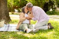 Happy senor european man and lady sit on plaid enjoy romantic date, husband kiss wife in park Royalty Free Stock Photo