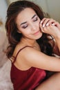 Happy sensual smiling girl asian young woman with dark long curly hair in red underwear sitting on bed Royalty Free Stock Photo