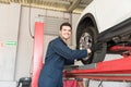 Happy Serviceman Removing Tire By Lift In Garage Royalty Free Stock Photo