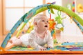 Happy seven months baby girl plays lying on colorful playmat