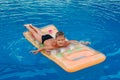 Happy seven-year-old boy lying on an air mattress in the outdoor pool in the summer. Blue water