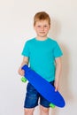 Happy seven-year-old boy in a turquoise t-shirt holding a new blue skate