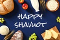 Happy Shavuot card. Flat lay dairy products, bakery, suits on blue background