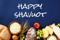 Happy Shavuot concept with dairy products and fruits on blue background