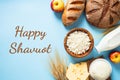 Happy Shavuot Jewish holiday concept. Dairy products, wheats, cottage cheese in bowl, cheese, bread, apples, bottle of milk on
