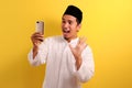 Happy Shock Young Asian Muslim man wearing muslim clothes holding mobile phone look at phone screen