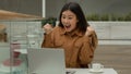 Happy shocked Asian woman businesswoman sit in cafe with laptop surprised chinese korean girl winner win job offer Royalty Free Stock Photo