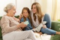 Grandmother holds gift box with present from grandchild girl and smiling daughter.