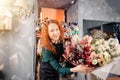 Happy shop assistant showing prepared rich floral bouquet at store