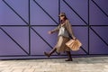 A happy shopaholic girl keeps her bags near the shopping center. A woman near the store is happy with her purchases