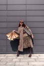 A happy shopaholic girl keeps her bags near the shopping center. A woman near the store is happy with her purchases