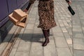 A happy shopaholic girl keeps her bags near the shopping center. A woman near the store is happy with her purchases