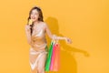 Happy shopaholic woman carrying shopping bags in colorful orange and yellow background Royalty Free Stock Photo