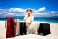 A happy shopaholic women opening a shopping bag on the beach