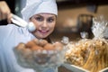 Happy shopgirl working with different pastry Royalty Free Stock Photo