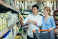 Happy shoppers Asian man and woman buy and choose goods in supermarket, family shopping. Royalty Free Stock Photo