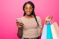 Happy shopping woman texting on her cell phone isolated over pink background Royalty Free Stock Photo