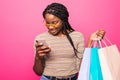 Happy shopping woman texting on her cell phone isolated over pink background Royalty Free Stock Photo