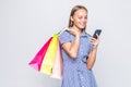 Happy shopping woman texting on her cell phone  over white background Royalty Free Stock Photo