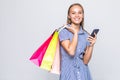 Happy shopping woman texting on her cell phone  over white background Royalty Free Stock Photo