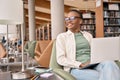 Happy African girl student using laptop sitting in university campus library. Royalty Free Stock Photo