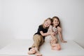 Happy siblings sitting together on table. Boy hugs girl, she leans away a bit Royalty Free Stock Photo