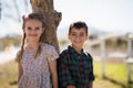 Happy siblings leaning on tree trunk in park Royalty Free Stock Photo