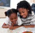 Happy siblings reading lying on the floor Royalty Free Stock Photo