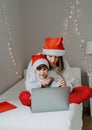 Happy siblings in red santa hats shopping online buying Christmas gifts paying by credit card