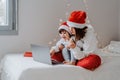 Happy siblings in red santa hats shopping online buying Christmas gifts paying by credit card using laptop