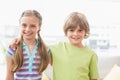 Happy siblings standing arm around at home