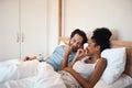 Happy, silly and goofy couple bonding in bed, sharing intimate relationship joke and moment. Young interracial husband Royalty Free Stock Photo