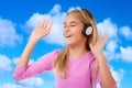 Happy singing teenage girl with headphones over blue sky background