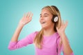 Happy singing teenage girl with headphones over green background