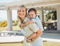 Happy single mother giving her little son a piggyback ride outside in a garden. Smiling caucasian single parent bonding Royalty Free Stock Photo