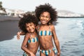 Happy sisters enjoying inside sea water during summer time - Afro kids having fun playing on the beach Royalty Free Stock Photo