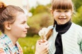 Happy sisters hold dandelions together in the park in the spring. Caring, loving older sister gives wildflowers to her younger