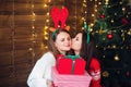 Happy sisters presenting gifts each other near Christmas tree Royalty Free Stock Photo