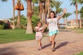 Happy sisters run on footpath in tropical resort. Sisters relaxing on vacations