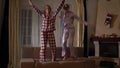 Happy sisters twins in pajams jumping on the couch in a cozy living room and having fun like in childhood. Relationship