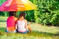 Happy sisters under colorful umbrella in park