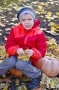 Happy boy sitting on pumpkin outdoors in autumn. Helloween. Royalty Free Stock Photo