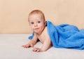 Happy six month old baby lying under the towel on a bed and having fun Royalty Free Stock Photo