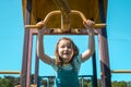 Happy six years old kid making sport outdoors. Little girl playing on playground, hanging walk along the monkey bars Royalty Free Stock Photo