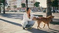 Happy skater stroking dog resting summer street. Carefree girl enjoying vacation Royalty Free Stock Photo