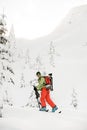 happy skier in bright jacket is climbing the hill using skitour equipment.