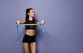 Positive weight loss diet results. Happy slim woman in sport wear with measuring tape on purple Royalty Free Stock Photo