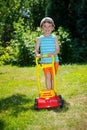 Happy small boy help with gardening with his lawn mower Royalty Free Stock Photo